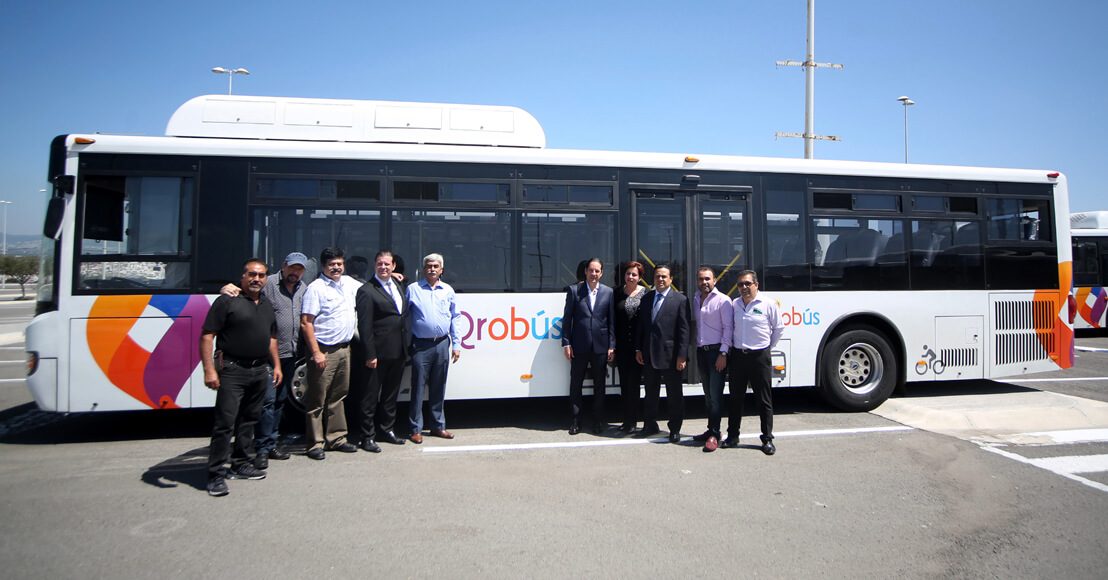 El entonces gobernador Francisco Domínguez y el entonces líder del proyecto de Qrobús, Luis Nava, con representantes de empresas concesionarias en Querétaro, posando delante de una unidad de transporte público.